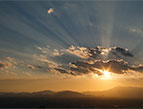 christmas Devotion picture of light bursting through the clouds above a mountaintop